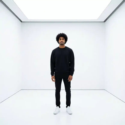 A men wearing a black sweatshirt standing in a white room